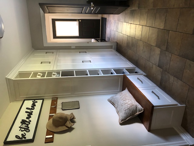 Painted MDF mudroom cabinets with custom wooden bench top and shoe cubbies.